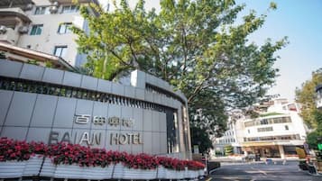 A hotel entrance with a curved facade, signage in two languages, and a parking lot in the foreground.