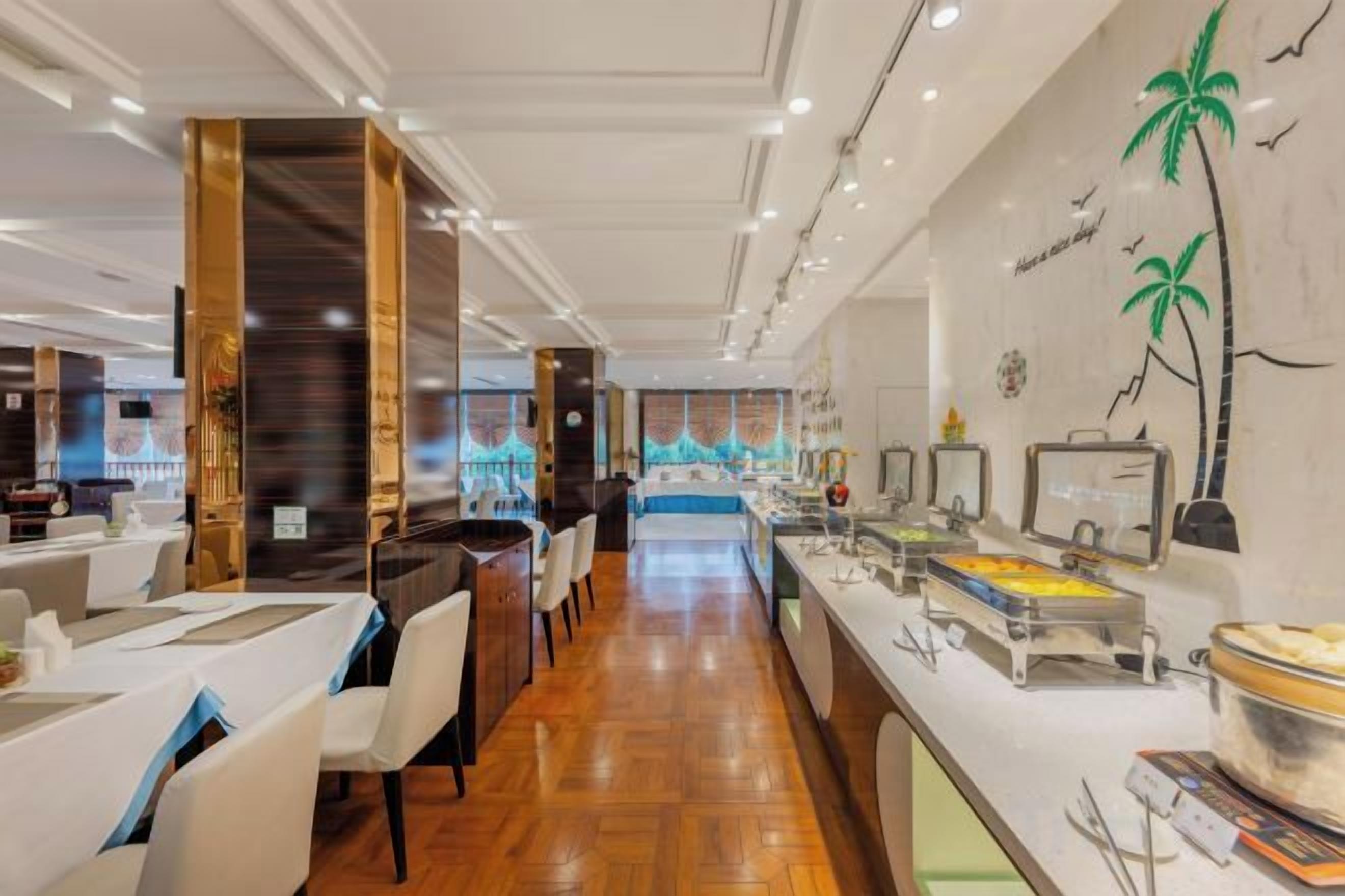 A hotel lobby with a long reception desk, seating area, and a buffet with various food items.