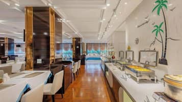 A hotel lobby with a long reception desk, seating area, and a buffet with various food items.