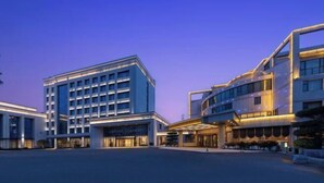Un hotel moderno con un cortile centrale, diversi piani e una facciata che combina vetro e muratura.