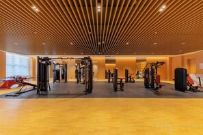 A gym with various exercise equipment, a wooden ceiling, and a large window. - Bai an Hotel (Chongqing)