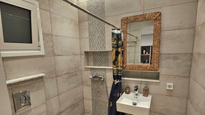 Ein modernes Badezimmer mit Toilette, Waschbecken, Dusche und Spiegel.