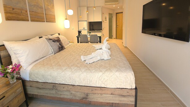 Ein modernes Hotelzimmer mit einem großen Bett, einem Flachbildfernseher, einem Schreibtisch mit Stuhl und Kunstwerken an den Wänden.