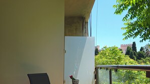 Ein Balkon mit Tisch und Stühlen, einer Ziervase und Blick auf eine entfernte Burg.