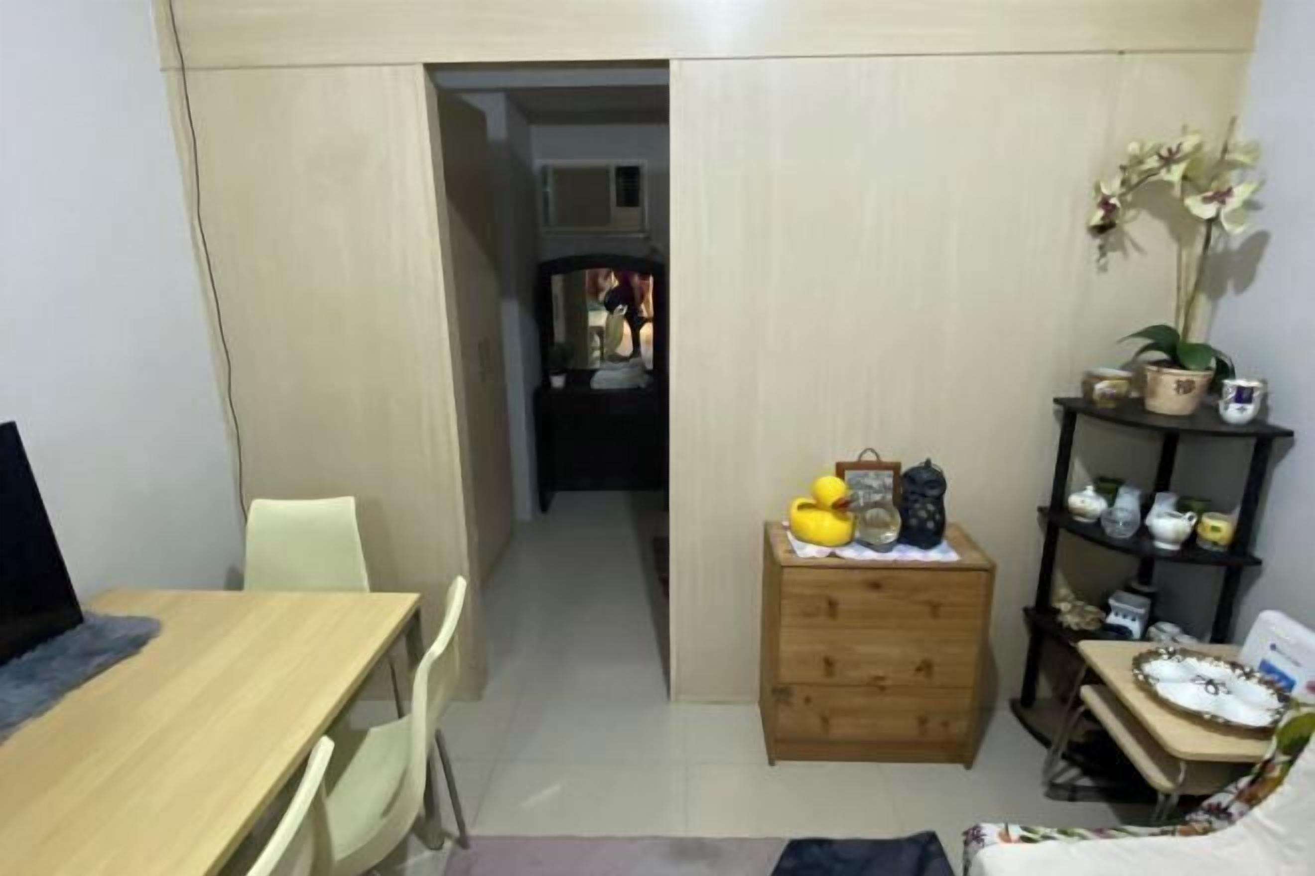 A compact room with a wooden desk, a chair, a small dresser, and a shelf with decorative items.