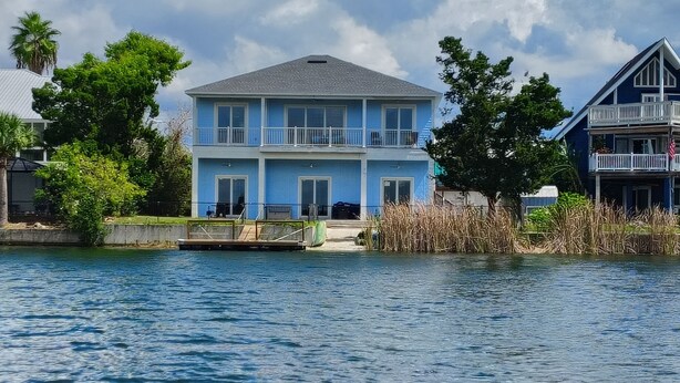 A two-story house with a balcony, situated by a body of water. - Waterfront and Gulfview Retreat Hernando Beach (Hernando Beach)