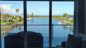 A room with a view of a lake, a balcony with a sofa, and a wooden deck. - Waterfront and Gulfview Retreat Hernando Beach (Hernando Beach)