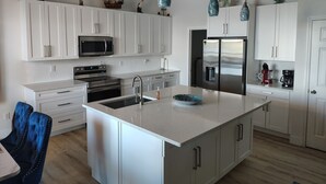 A modern kitchen with white cabinetry, stainless steel appliances, and a central island. - Waterfront and Gulfview Retreat Hernando Beach (Hernando Beach)