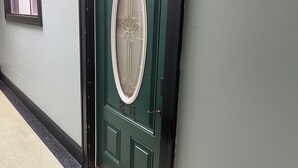 Een groene deur met een ruit en een klein raam.