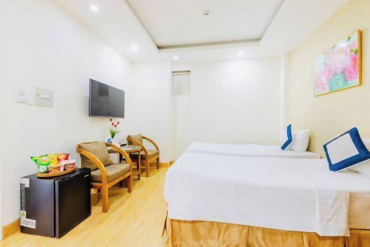 Une chambre d’hôtel avec deux lits, une télévision, un petit réfrigérateur et un bureau avec des chaises.