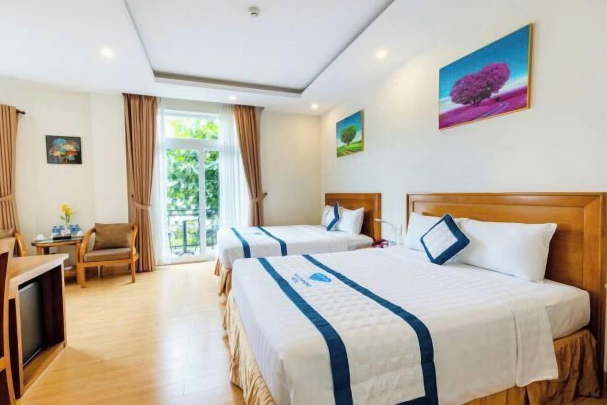Une chambre d’hôtel avec deux lits, une télévision, un bureau et une fenêtre avec des rideaux.