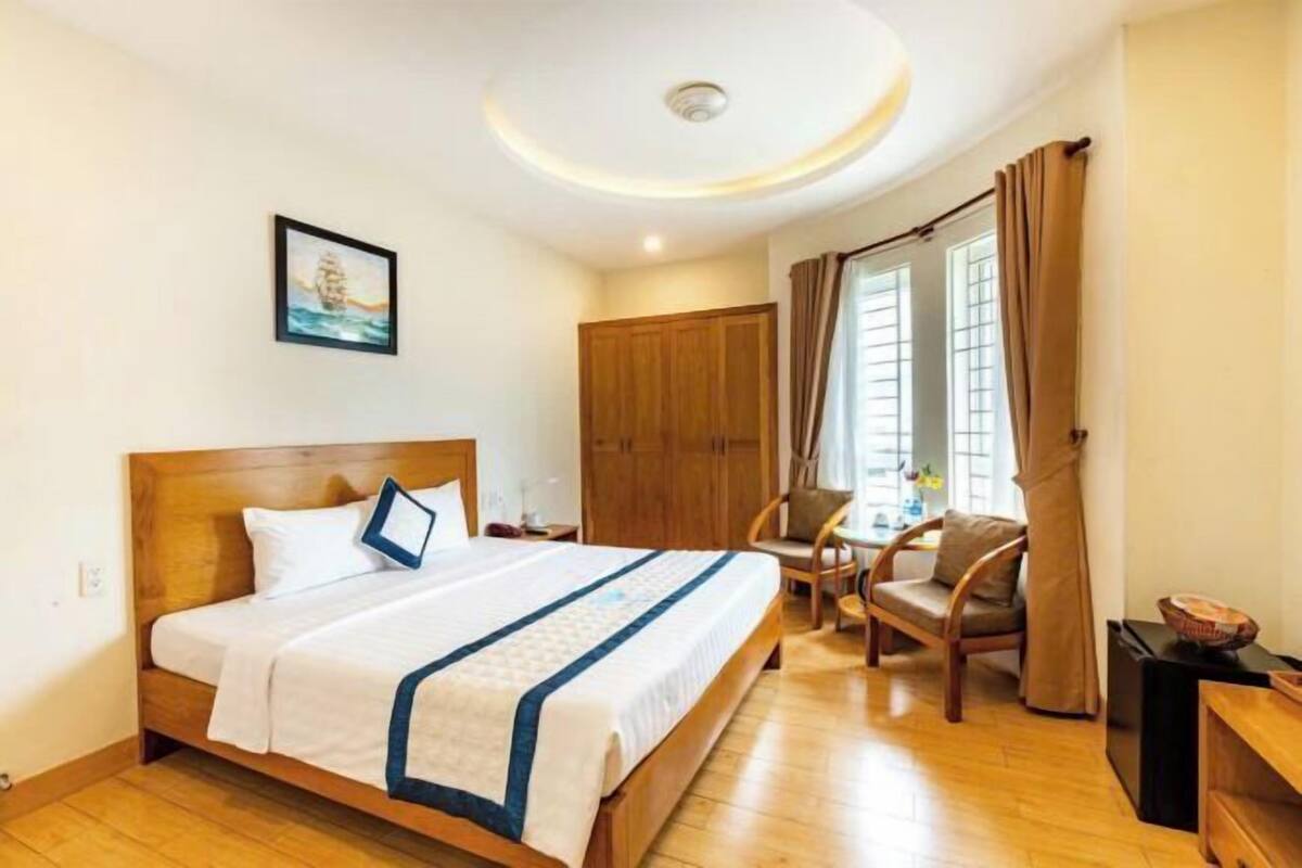 Une chambre d’hôtel avec un lit en bois, un bureau, une chaise et une armoire.