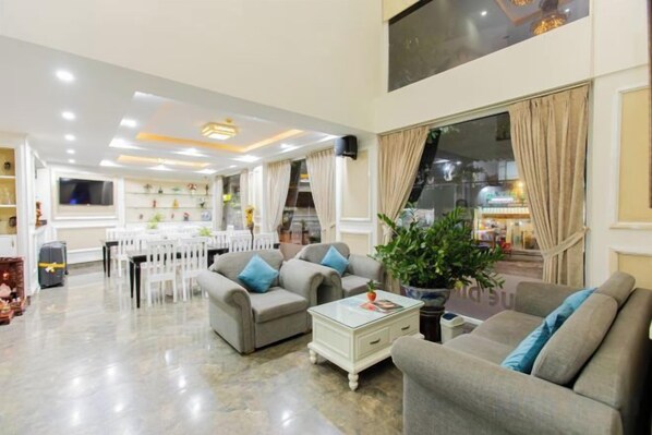A spacious living area with a dining table, sofas, and a large window.