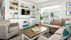 Ein Wohnzimmer mit Sofa, Couchtisch und einem an der Wand befestigten Fernseher.