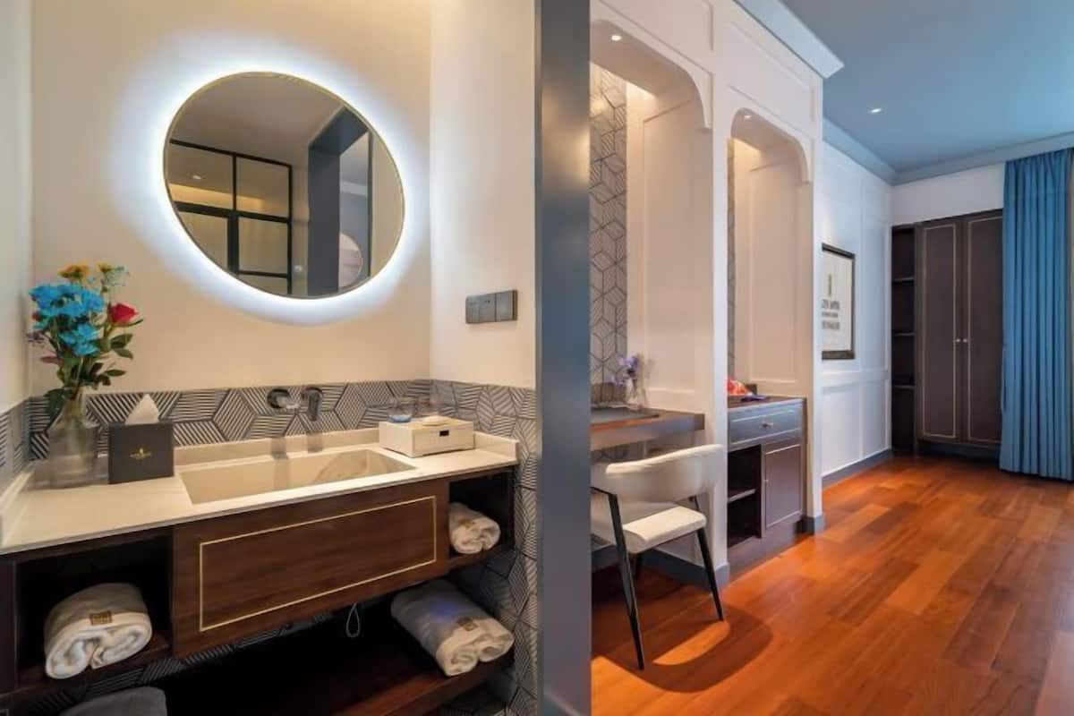 A modern bathroom with a double sink vanity, a round mirror with lighting, and a shower area.