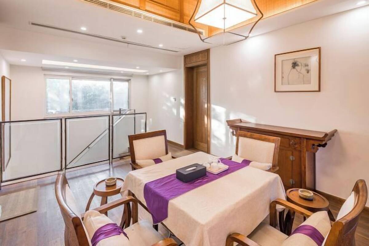A hotel room with a bed, a desk, and a chair. There is a window with a view of trees.