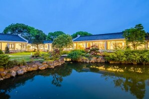 A traditional building with a pond in front, surrounded by greenery. - Jiulong Bay Garden Rezen Hotel (Wuxi)