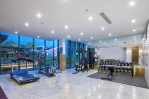 A modern gym with cardio equipment, weight machines, and a rowing machine. - Jiulong Bay Garden Rezen Hotel (Wuxi)