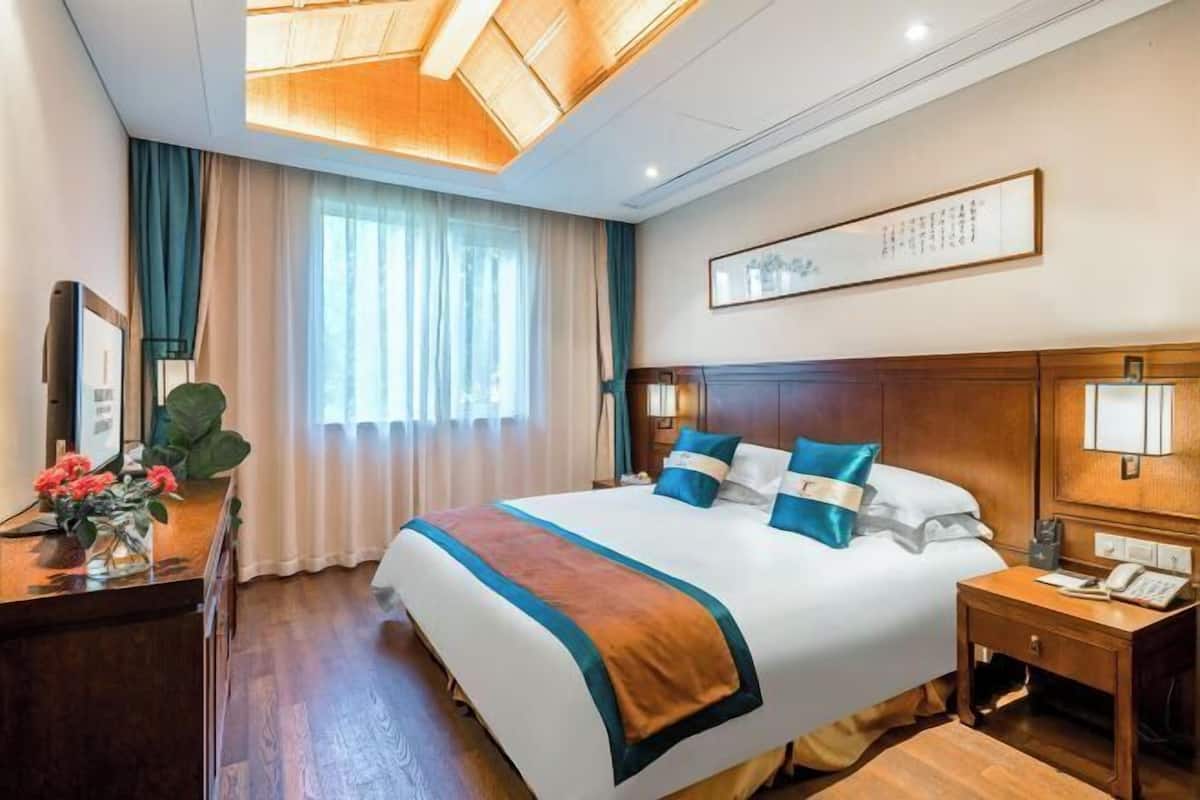 A hotel room with a large bed, a desk with a telephone, and a window with curtains.