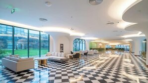 Un vestíbulo amplio con piso a cuadros, ventanas grandes y muebles modernos.