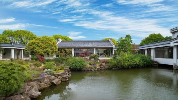 Un edificio tradicional japonés con un estanque de carpas koi y abundante vegetación.