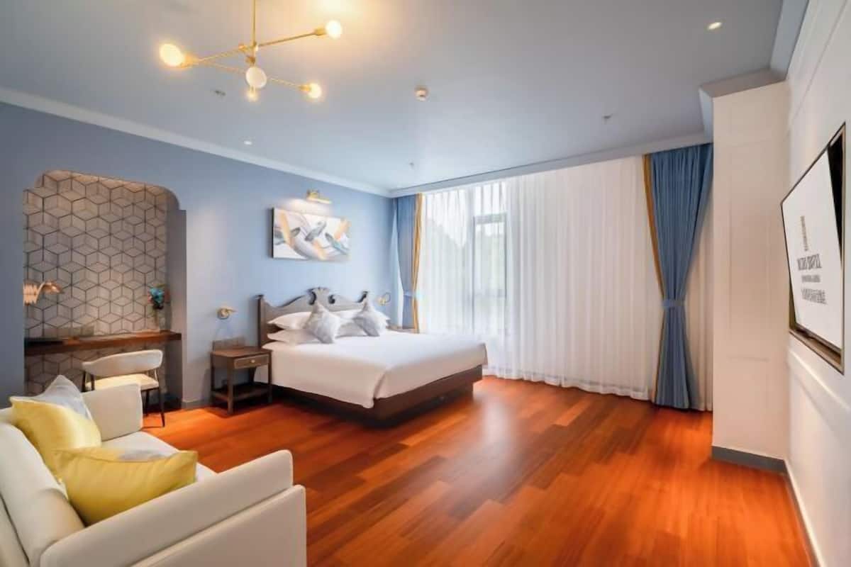 A modern bedroom with a large bed, a desk, and a sofa.