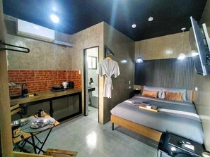 A compact hotel room with a kitchenette, a bed with pillows, a TV, and a hanging robe. - Standard room/Casakarina-Lucena City (Lucena City, Quezon)