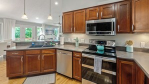 Une cuisine moderne avec des meubles en bois, des appareils électroménagers en acier inoxydable et des luminaires suspendus.