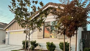 A residential house with a garage, a driveway, and a landscaped front yard with trees and shrubs. - ROSEVILLE GETAWAY (Roseville)