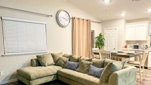 A living room with a sectional sofa, a dining area with a table and chairs, and a kitchen in the background. - ROSEVILLE GETAWAY (Roseville)