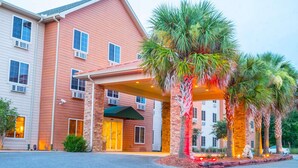 A hotel with a red facade, a covered entrance, and palm trees.