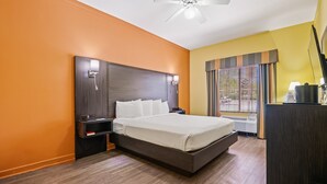 Ett hotellrum med en stor säng, sängbord, en takfläkt och ett fönster med persienner.