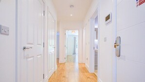 A hallway with white doors and wooden flooring. - Hybridresi New Malden (New Malden)