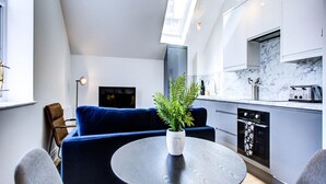 A modern kitchen with a marble countertop, a built-in oven, and a dishwasher. - Hybridresi New Malden (New Malden)