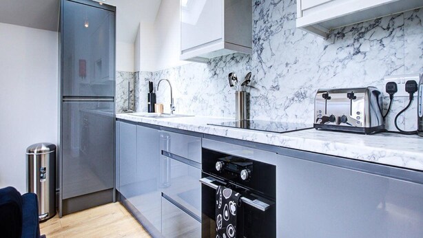 A modern kitchen with a marble countertop, stainless steel appliances, and a skylight. - Hybridresi New Malden (New Malden)