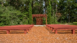 Um gazebo de madeira com design treliçado numa área arborizada.