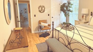 Ein Schlafzimmer mit Bett, Stuhl, Schreibtisch und einer Pflanze.