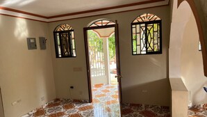 Un passadís amb rajoles de terra estampades, un ventilador al sostre i una porta que dona a zona exterior.