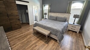 A bedroom with a bed, bench, nightstands, and a closet with a sliding door. - Beautiful Hampton Lakes Home - RECENTLY RENOVATED (Davenport)