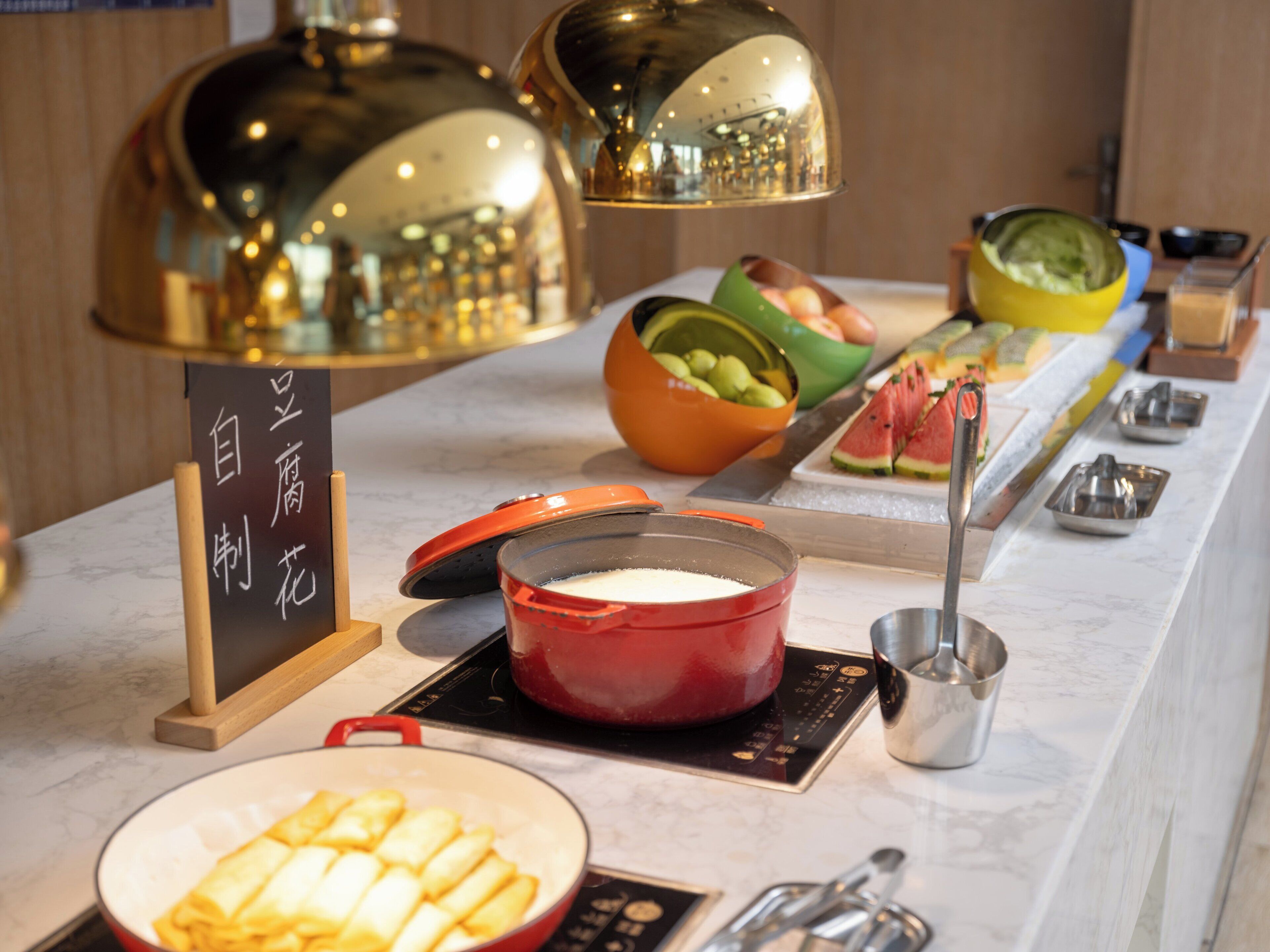 A buffet setup with various food items and cooking equipment.