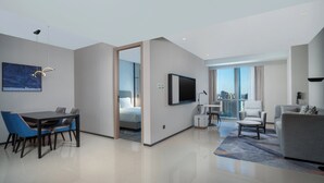 Une chambre d’hôtel moderne comprenant un coin repas, un salon et un balcon avec vue sur la ville.