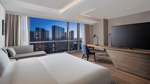 Une chambre d’hôtel moderne dotée d’un grand lit, d’un bureau, d’une chaise, d’une télévision et offrant une vue sur la ville.