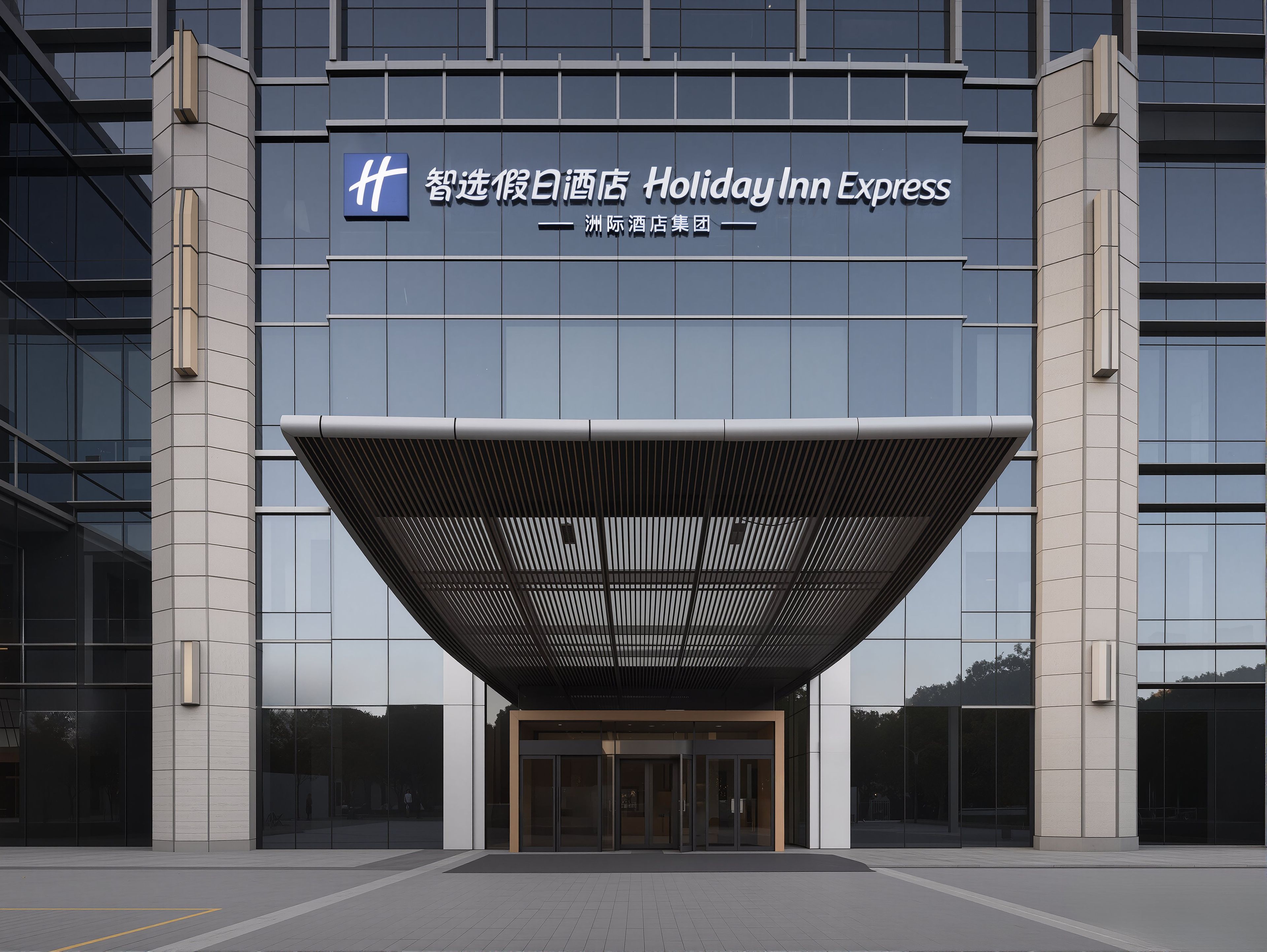 A modern building with a Holiday Inn Express sign, featuring a prominent entrance with a unique roof structure and large glass windows.