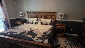 A bedroom with a wooden bed, a ceiling fan, a nightstand, a lamp, and a rug. - Family Times Cabin (Sevierville)