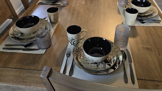 A dining table set with multiple bowls, cups, and a candle centerpiece. - Family Times Cabin (Sevierville)