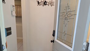A hallway with a welcome mat, a door with a glass panel, and a wall-mounted welcome sign. - Family Times Cabin (Sevierville)
