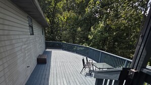 A wooden deck with a railing, a bench, and a table. - Family Times Cabin (Sevierville)