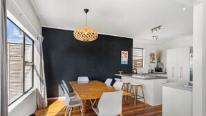 Una cocina moderna con una mesa de comedor de madera, sillas blancas y una pared de acento negra.