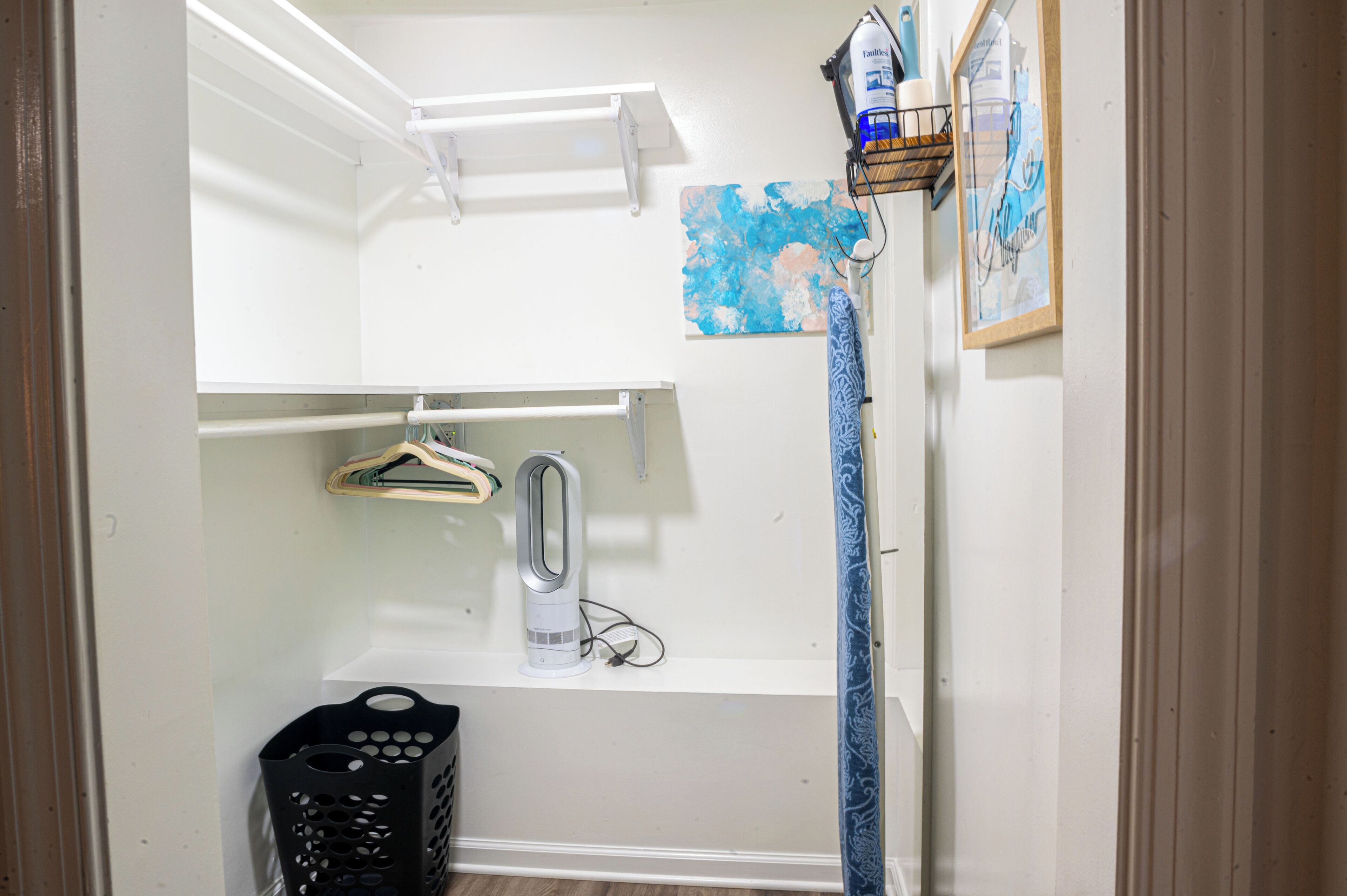 Une petite salle de bain propre, avec un lavabo blanc, un porte-serviettes, une serviette suspendue, un rideau de douche et une œuvre d’art encadrée accrochée au mur.