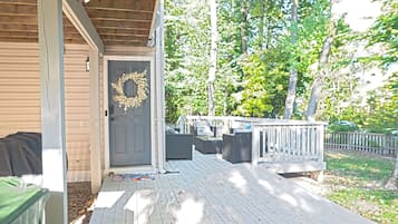 A wooden deck with outdoor seating, a door with a wreath, and a fenced yard.